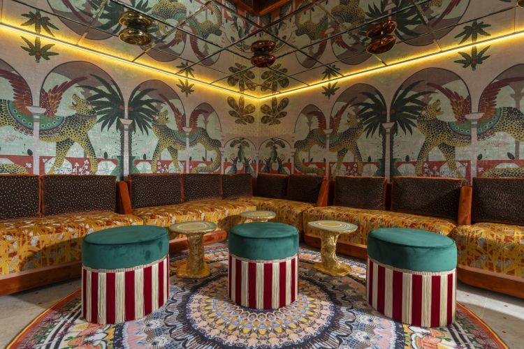 Il nuovo lounge bar interno dell'hotel con preziosi tavolini in foglia d'oro e ceramica ed eleganti pouf con frange
