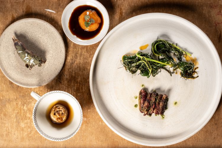 Petto di Germano alla mediterranea, cozze e agretti
Il petto di germano è marinato, cotto alla brace, condito da un intingolo mediterraneo e fondo di germano, con crema di agretti e agretti alla brace. Accanto, c'è un tortello alla brace stile gyoza ripieno di interiora e duroni, un tuorlo di estratto di arancia e fondo di germano a evocare l’anatra all’arancia, e la coscia ripiena di prugna sottaceto e spolverata da erbe
