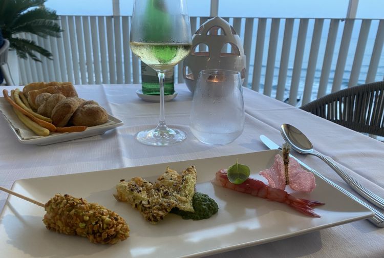 Aperitivo di benvenuto con scampo fritto in granella di pistacchi, acciughe impanate e pesto genovese, gambero viola e cialda di barbabietola