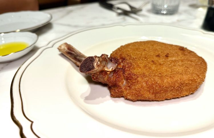Cotoletta di vitello alla milanese. Dopo la prima panatura, la carne è messa a risposare 2/3 giorni sottovuoto. Segno particolare: non c'è scollamento tra la panatura e la carne