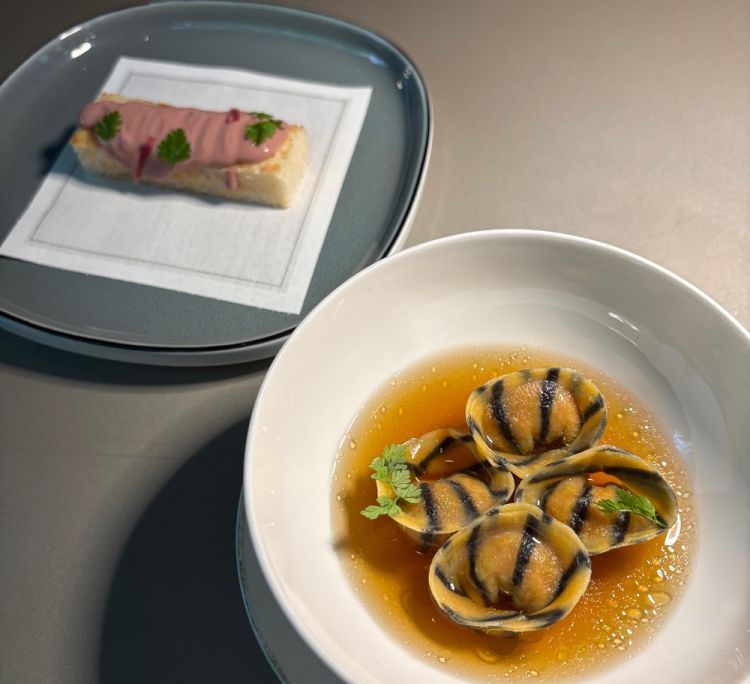 Patè di fegatini d’anatra e Tortellini di coscia d’anatra arrosto – «Il colore rosa del patè si deve a una particolare salagione, una marinatura veloce che esalta il sapore dei fegatini, insieme a una riduzione di vino. Il tortellino è farcito con la coscia confit e con cipolla anch’essa confit. Il brodo, preparato anche con la carcassa dell’anatra, viene ridotto per renderlo più intenso»