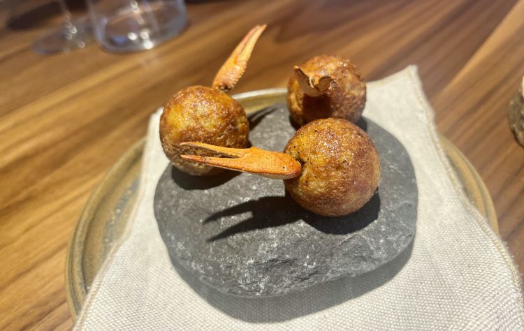 Gambero di fiume
Takoyaki ripieno di una bisque calda di gambero americano, olio e maionese leggermente piccante da estrazione di kimchi e una parte di salame autoprodotto. Un esordio molto goloso, come si può immaginare, con uno sfondo sociale: «Il gambero americano», spiega bene Cazzani, «è una specie invasiva: si diffuse in Europa alla fine dell'Ottocento, soppiantando il crostaceo locale». La dieta alpina può benissimo integrare elementi infestanti e alloctoni, un ragionamento che Lazzarini condivide con i colleghi e amici Francesco Brutto e Chiara Pavan di Venissa
