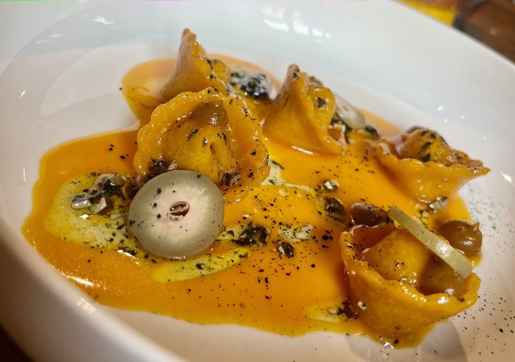 Un altro primo piatto speciale: Raviolo aromatizzato alla zucca e ',nduja ripieno di corgonzola liquido e aglio orsino, legato con estratto e mostarda di zucca, semi soffiati e delle rondelle croccanti di paschiole in salamoia