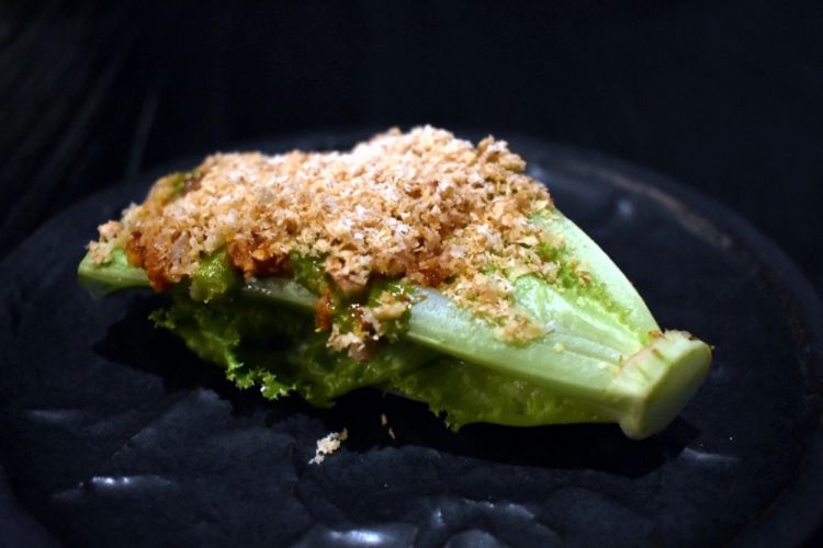 Può il grumolo di una lattuga cruda diventare un assaggio di un ristorante fine dining? Un boccone da portarsi alla bocca usando le mani, prendendolo per il cespo come si trattasse della coda di un gambero. Croccante, rinfrescante e saporitissimo grazie alla crema di funghi, al formaggio mantecoso e al chimichurri (salsa liquida che accompagna ogni asado che si rispetti, nella versione tradizionale a base di prezzemolo, origano, aglio, aceto, olio, sale e peperoncino) arricchito da noci, mandorle e da erbe della vegetazione nativa