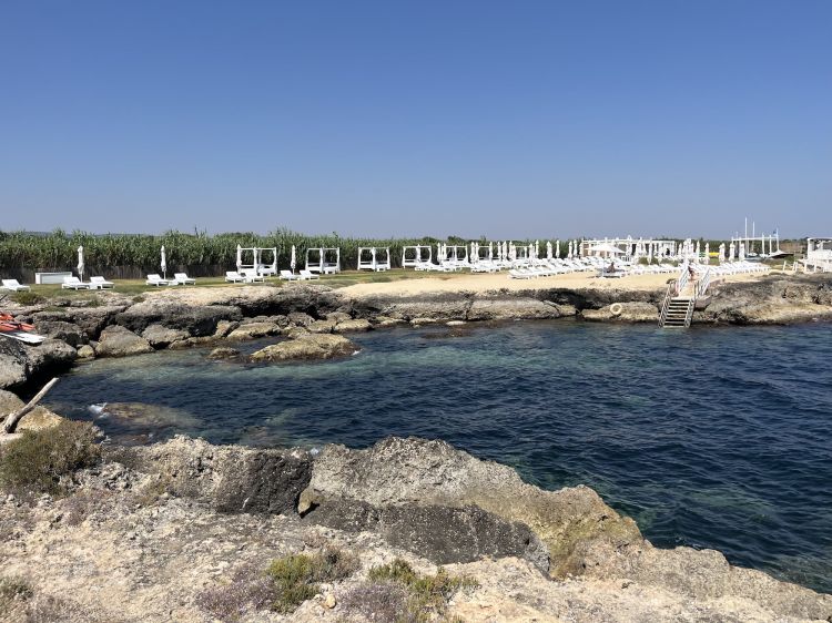 La vista scogli e mare blu di Cala Masciola. Il beach club contiene anche La Baracca, un piccolo locale più easy, di prodotti e semplici insalate
