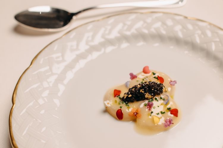 Capasanta con beurre blanc e caviale italiano abbinata a un un triplo brodo di pollo di Bress. È un evidente omaggio alla cucina francese per tecniche e materie prime: si va dal goloso contrasto sapido-lattico del piatto alle tonalità potentemente umami del brodo. Un gioco di succulenze indotte dai gusti marini del caviale e dalla vibrante concentrazione dell’estratto liquido
