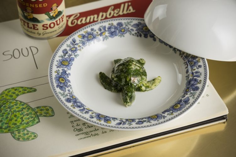 Dai menu degli anni '70, Zuppa di tartaruga: l’iconica forma di una tartaruga si trasforma in una minestra di verdure, foglie spontanee siciliane di stagione ed erbe selvatiche amaricanti, servita con un caldo consommé che ne scioglie la forma