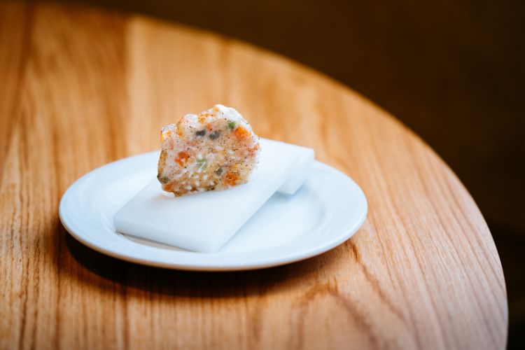 I piatti del menu della serata Cracco/Baronetto alla Dispensa di Torino. Dopo un trancio di focaccia al lardo con consommè di ceci, ecco l'Insalata russa caramellata, sigillata con cannello in due dischi di isomalto. Concepita nel 2001, è l'unico piatto mai uscito dal menu del ristorante Cracco
