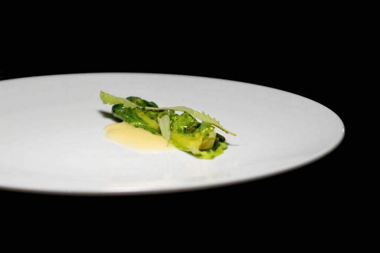 Lattuga alla brace, pepe verde e luppolo. La conclusione salata del percorso &egrave; di enorme livello: foglie di lattuga cotte alla brace, sotto la verdura si trova il pepe verde, mentre il luppolo viene impiegato nella salsa. Dopo la profondit&agrave; dell&rsquo;agnello, la lattuga agisce quasi come una pulizia del palato. La brace aggiunge una componente affumicata, il pepe imprime una vibrazione speziata e il luppolo prolunga l&rsquo;amaro. &Egrave; una preparazione apparentemente minimale, ma collocata con precisione nella scansione del menu. &Egrave; lunga in bocca, aromatica e floreale, balsamica e amara. Coraggiosa

Segue una selezione di formaggi: il primo &egrave; un taleggio di capra realizzato dalla famiglia Serra a San Giovanni in Fiore. I produttori allevano gli animali seguendo metodi simili a quelli adottati da Maria Procopio, figura di riferimento della caseificazione calabrese. Poi un carosello di tre erborinati, uno per ciascun latte: un roquefort di pecora; un formaggio di capra della stessa&nbsp;Maria Procopio; un erborinato vaccino del caseificio Dicecca, in Puglia. La selezione si conclude con il pecorino di fossa della famiglia De Tursi, a Strongoli. Il formaggio segue inizialmente una lavorazione vicina a quella del pecorino crotonese, con circa cinque mesi di affinamento sulle assi; viene poi collocato in fossa per un periodo compreso tra due anni e mezzo e tre anni. Ad accompagnare i formaggi, un pane&nbsp;preparato con farina di castagna tostata, miele di castagno e uva passa. La componente morbida e dolce viene completata da una marmellata ai mandarini, liquirizia e cedro
