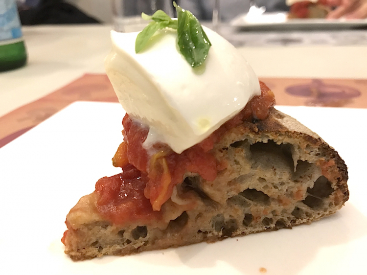 Uno spicchio di pizza Bufalina: Pomodoro San Marzano "Terra Amore e Fantasia", Mozzarella di Bufala Campana DOP, basilico fresco. Impasto idrolisi e per completare la bontà olio pugliese Intini, fruttato 2017
