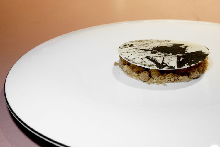 Marble gress, omaggio al locale distretto della ceramica. Il disco di cioccolato bianco nasconde un crumble alle mandorle, fichi canditi, sciroppo di spezie, salsa di ribes, neve ghiacciata di more