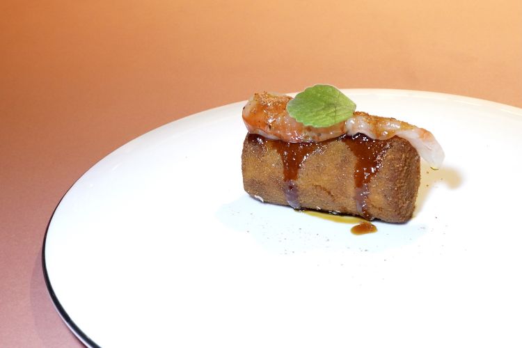 Ali di pollo e gamberi. Le ali sono cotte sottovuoto, riassemblate e poi fritte, condite con una glassa di miele, limone e pepe. Il gambero è crudo, poi foglie di origano cubano. Idea gustativamente interessante ma il boccone manca troppo di umidità
