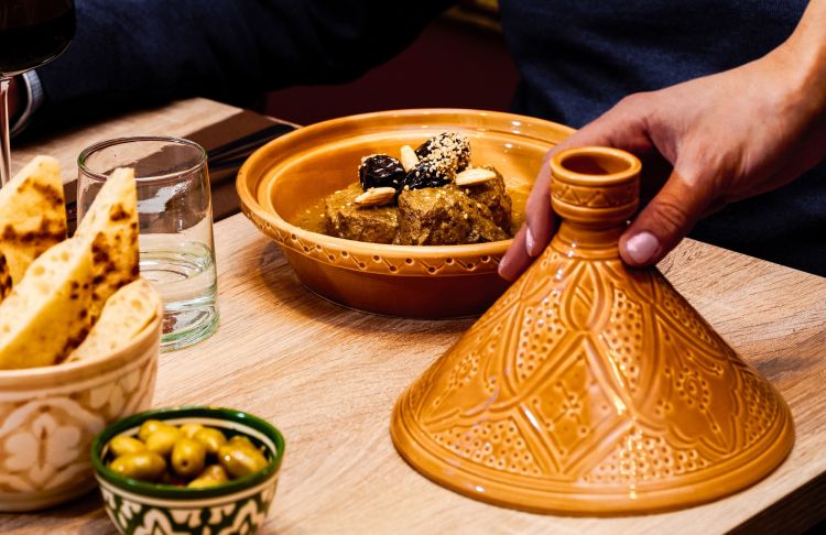 Tajine Barkouk: manzo cotto lentamente, fino a diventare morbido e succoso, in una salsa speziata con note di cannella e zafferano. Le prugne aggiungono una dolcezza naturale che si bilancia con la sapidit&agrave; della carne, mentre mandorle e sesamo tostato completano il piatto con una nota croccante
