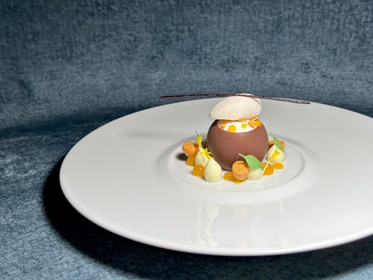 Dopo il pre-dessert (Granita di mentuccia romana: brunoise di pesca sciroppata, granita di mentuccia romana e champagne) ecco Ananas, cocco, kiwi: sfera di cioccolato fondente, burro di cacao, ananas confit, quenelle di gelato di cocco, banana e lime. All’interno, a replicare la Piña Colada, un goccio di rum
