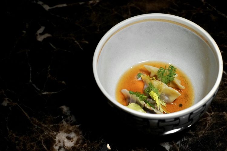 Ripartiamo dal brodo: three dumplings, the first with roasted celery, the second with burnt carrot, the third with onion cooked in salt. On the base a black garlic oil and vegetable dashi broth made from celery, carrot and onion
