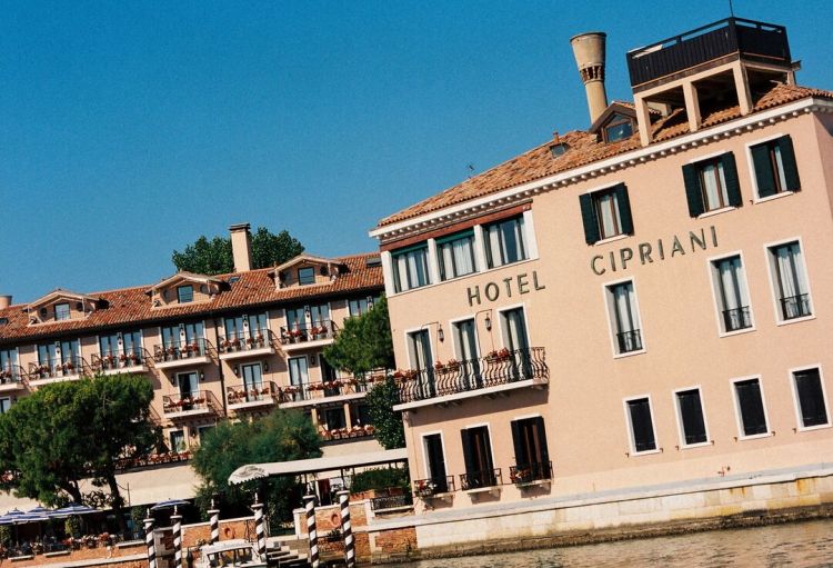 Il mitico Belmond Hotel Cipriani della Giudecca di Venezia. L'hotel - tra i più prestigiosi in assoluto - è interessato a un progetto di rinnovamento pluriennale affidato a Peter Marino, architetto e interior designer americano molto legato alla città anche attraverso Venetian Heritage. L’idea non è rifare l’hotel da zero, ma aggiornarlo per fasi preservandone il carattere, mettendo insieme memoria della Dolce Vita, tradizione veneziana, arte contemporanea e maggiore comfort. La prima fase, completata e presentata nel maggio 2025, ha riguardato soprattutto l’arrivo in hotel e 13 camere e suite. Marino ha lasciato intatta la storica reception in legno, ma le ha affiancato una nuova lobby a doppia altezza, molto luminosa, che crea un collegamento più scenografico tra il giardino della fontana e la zona piscina. Sono state inoltre completamente ridisegnate 13 sistemazioni: le due master suite Serenissima e Laguna, concepite come veri appartamenti veneziani con salotto, sala da pranzo e biblioteca, più 11 suite e junior suite affacciate sui Giardini Casanova. La seconda fase è quella che si è concretizzata nel 2026. Sempre su progetto di Marino sono arrivati due interventi molto importanti: la nuova Dior Spa e il restyling completo del ristorante Oro. La spa, inaugurata nell’estate 2026, è la prima Dior Spa di Venezia: si sviluppa su due piani, con cinque cabine trattamento e boutique, e combina codici estetici veneziani con il linguaggio Dior. Anche Oro è stato completamente ripensato da Marino. Il ristorante mantiene il rapporto spettacolare con la laguna, ma ora ha un’identità molto più marcata, con vetro di Murano lavorato a mano, nuove superfici, un soffitto fortemente scenografico e un impianto decorativo che insiste sull’idea dell’oro e della luce veneziana. Il piano non è concluso: il progetto dell'architetto è esplicitamente pluriennale e riguarda progressivamente l’intero hotel, in particolare il resto delle camere e delle suite: i lavori continueranno, per step, per altri quattro anni