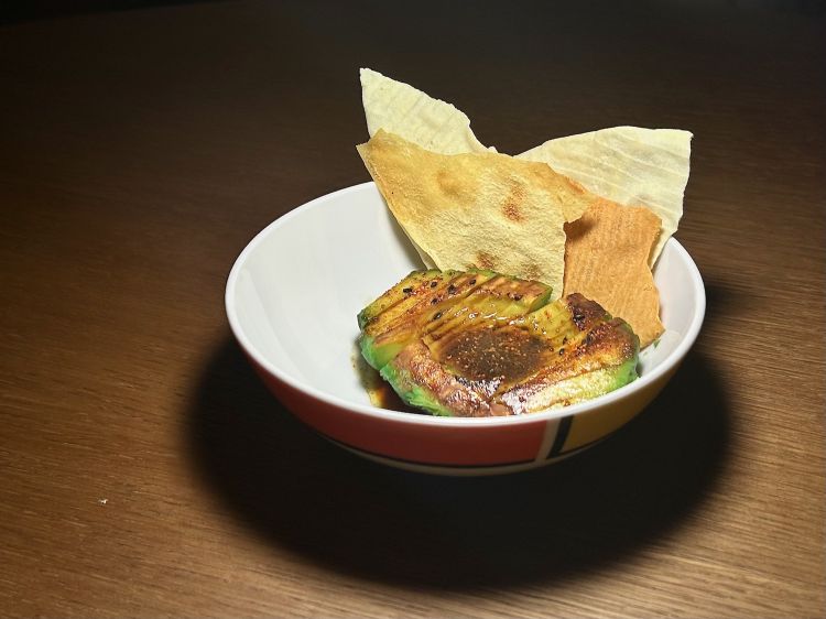 Avocado grigliato con salsa miso e togarashi, accompagnato da pane carasau