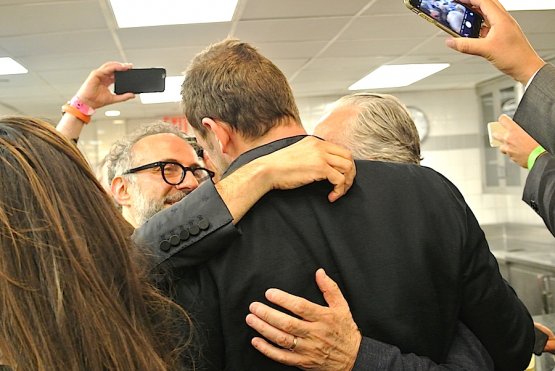 Massimo Bottura, Daniel Humm (the giant, from behind) and Alain Ducasse hugging at midnight in the kitchen of Eleven Madison Park in Manhattan
