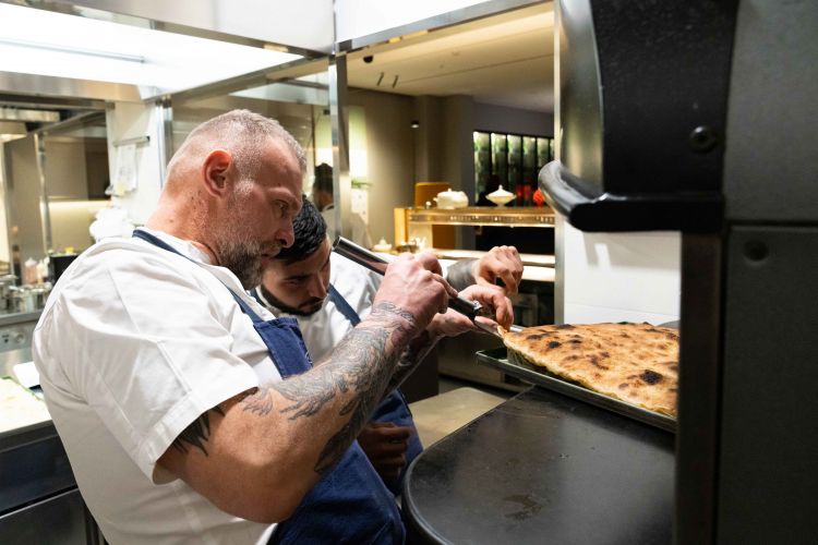 Al forno, Gabriele Bonci controlla la cottura della pizza romana pronta per essere farcita con ingredienti selezionati con cura e accostamenti mai scontati
