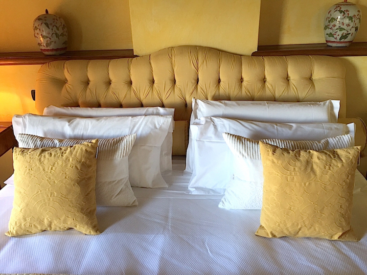 Gli otto cuscini disposti sul letto matrimoniale della stanza 25 di Casa Pavesi a Grinzane Cavour
