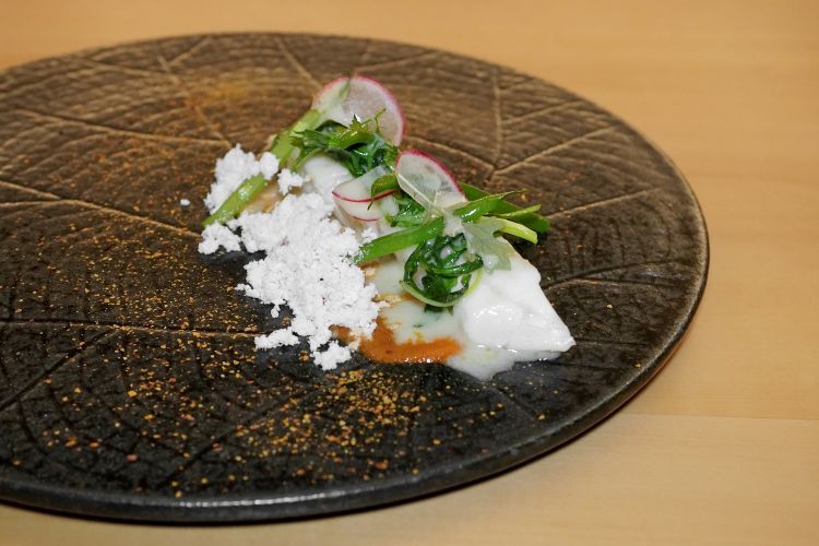 Ottima Spigola con concentrato di pomodoro, rucola saltata, fagiolini, ravanelli e malto al pomodoro, il tutto condito con una salsa di lische di pesce tostate e poi cotte con acqua di pomodoro (a fine cottura il tutto viene filtrato, raffreddato ed emulsionato con succo di lime e olio evo). La spigola è frollata per una settimana e poi lasciata macerare per un giorno in alga kombu tostata a forno