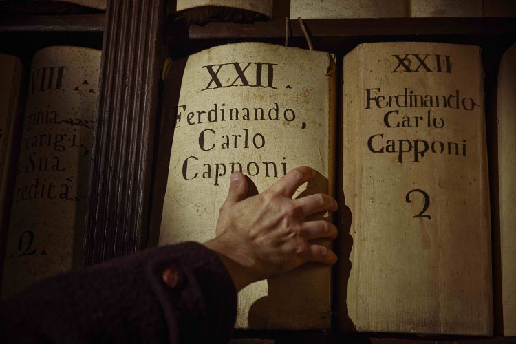 Da dove deriva il cognome "Capponi"? Tutto ebbe inizio nel Medioevo quando, con la crescita demografica e l'urbanizzazione, diventò cruciale identificare le persone in modo univoco andando oltre oltre il semplice nome, specialmente per la trasmissione dei beni ereditati. Il cognome "Capponi" deriva da un soprannome personale, evidenziando così la discendenza. La citazione del 1052, Ugutius filius Gini qui Cappone vocatur ovvero “Uguccione figlio di Gino detto Cappone”, è significativa poiché introduce due nomi di famiglia ricorrenti nei secoli e soprattutto il soprannome che diventa cognome. Varie forme del cognome si uniformarono nel tempo: da "Compagnus de Capponis" nel 1246 ad "Andrea Capponis de Capponibus" nel 1360, fino ad arrivare ai giorni nostri. L'animale cappone divenne totemico e venne usato come simbolo su monete e dipinti da membri della famiglia Capponi. Tuttavia, amici (e nemici) spesso scherzavano sui membri della famiglia, come nel caso di Luigi di Niccolò Capponi, erede anche dei beni di Francesco Della Stufa, che fu soprannominato "Capponcino stufato". Come non menzionare infine Carlo VIII che si riferì ironicamente a Pier Capponi come "mauvais chapon”, per la sua testardaggine tipicamente fiorentina
