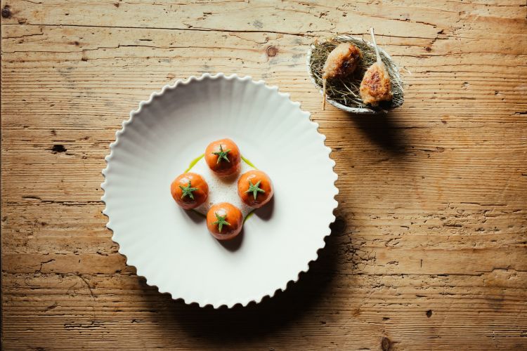 Cosce di ninfa alla Bella Aurora: «Riprendiamo un grande classico di Escoffier, l’aveva servito per il principe di Scozia, quindi coscia di rana con una salsa classica. Abbiamo lavorato molto su pomodori in varie consistenze e acidità, abbiamo creato uno gnocco di pomodoro ripieno di salsa Aurora (datterino alla brace, creme fraiche e mascarpone) e un beurre blanc all’acqua di pomodoro»