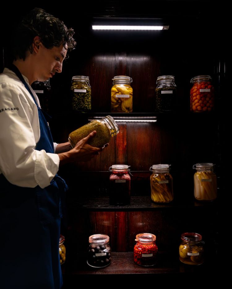Mattia Pecis ripreso nella sala dei conservati: lo chef ha approfondito e ripreso la consuetudine di mettere in conserva o sotto soluzioni di vario tipo frutta e verdura, per estrarre al massimo il buono che portano dentro di loro