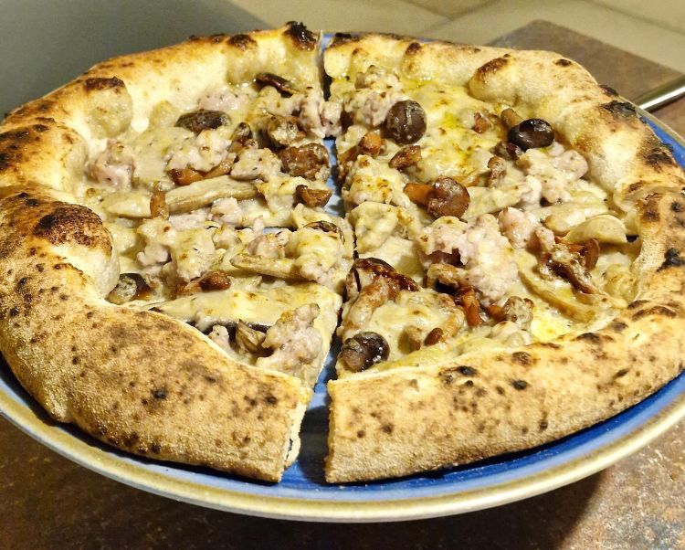 La pizza Creme brulèe, con funghi misti, panna bruciata ai porcini, salsiccia di maialino e Parmigiano Reggiano
