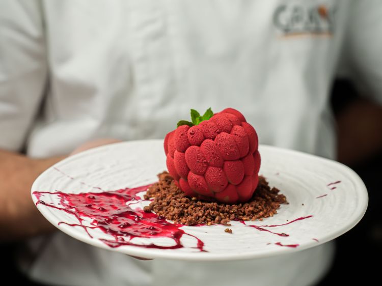 Carta dolci molto creativa: ecco il godurioso Cuor di lampone, un frangipane al pistacchio con mousse al cioccolato fondente e gelèe al lampone servito su terra al cacao e salsa ai frutti di bosco
