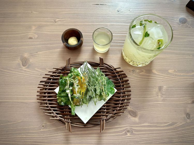 Il benvenuto: Foglie fritte in pastella leggera, maionese alla senape, idrolato di limone al basilico; il tutto è unito a un gradevolissimo e rinfrescante cocktail chiamato Elder fizz: sciroppo e fermentato di fiori di sambuco, succo di lime spremuto fresco e indian tonic, a ricordare un Hugo. Sorprendente e geniale il voler servire delle foglie e dei fiori fritti, cosa che fa già intuire la levatura di questa cucina