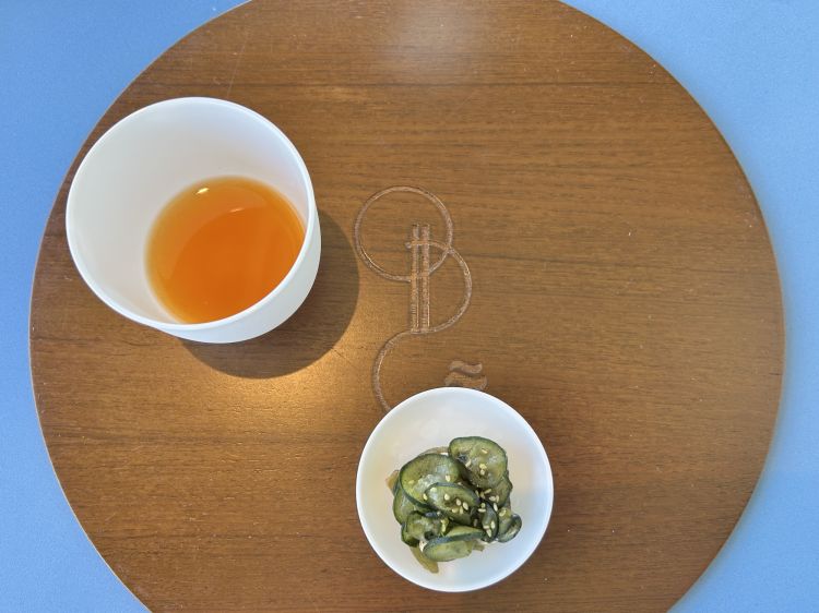 Lattuga croccante, cetrioli marinati, gel di cetriolo, maionese alla bottarga e semi di sesamo. Nella coppa un infuso freddo preparato con acqua di pomodoro, bitter e tè nero affumicato