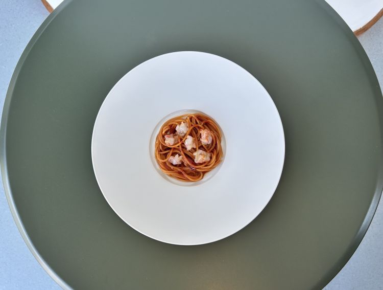 Spaghettini freddi, peperone e gambero rosso: è un piatto d’estate. «In fondo, tutto il menu racconta un po’ l’Italia attraverso microsapori: il limone, l’alloro, il geranio, la rucola e il pinolo, che nello scampo diventava quasi una componente lattica». I peperoni vengono arrostiti sulla brace, poi lavati, tagliati a listarelle e conditi con olio d’oliva e prezzemolo. In questo caso si usano peperoni rossi: se ne estrae il succo, lo si riduce e vi si cuoce la pasta. Il gambero rosso regala anche una parte grassa; alla base ci sono prezzemolo e olio d’oliva