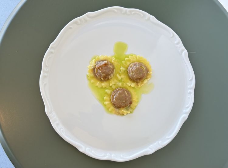 Tortelli di albicocca, rafano e ruta: le albicocche fresche vengono cotte in forno con un po’ di sale. La farcia, leggermente acidula, con una punta di rafano bianco, viene completata con albicocche sotto sale e albicocche essiccate, che regala una parte più dolce. Il tutto viene racchiuso in una pasta molto sottile. Sotto c’è la deglassatura della teglia, leggermente bruciacchiata, trasformata in un gel di albicocca, con rafano e ruta