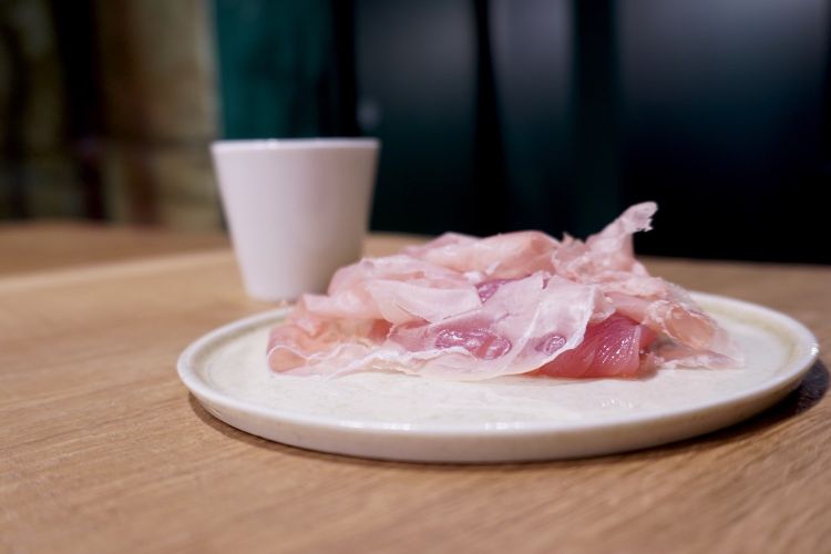 Sashimi rosso all'italiana: prosciutto di Parma e tonno marinato in una «salsa segreta», come ci spiegano. S'accompagna con un brodo di capperi di Noto
