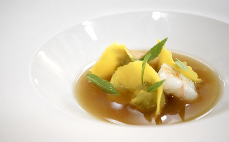 Tortello di melanzane, scampi ed erbette. Il brodo è fatto con quattro tipi di melanzane diverse: bianca, tonda, Sicilia e lunga. Nella versione originale lo scampo è sostituito con ricci di mare, che chiuderebbero anche meglio il gusto al palato