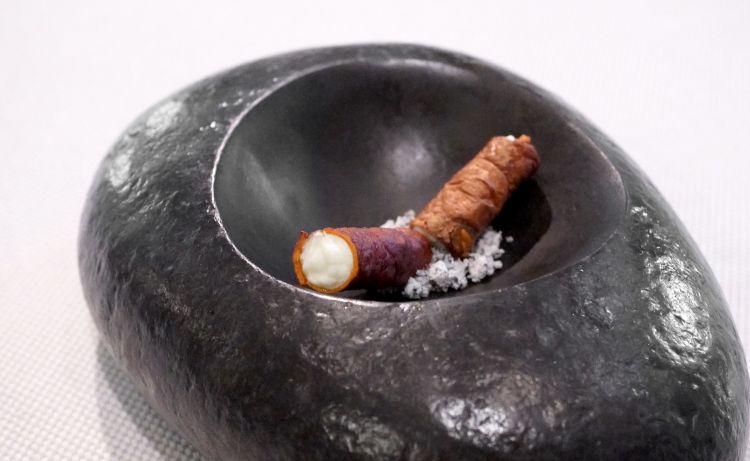 Sigaro di patate, caprino alle erbe e cenere di cipolle. Il sigaro è ottenuto con le bucce di patata