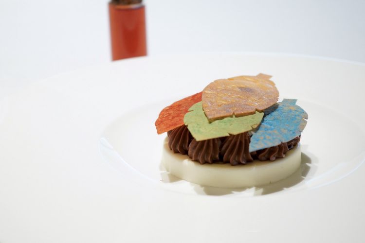 Chiudiamo con un omaggio a Magritte (e all'esperienza dello chef in Belgio): il piatto si chiama Fuoco e si compone di cremoso allo yuzu, ganache all'olivello spinoso, riduzione di birra scura, speculoos, crumble di limone e cannella, foglie di mela croccanti. Un assaggio per niente banale
