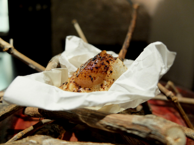 Spiedino di rana pescatrice, polvere di aglio nero, crema di umeboshi. Ancora un gran piatto, si sorseggia un eccezionale succo di rabarbaro Van Nahmen
