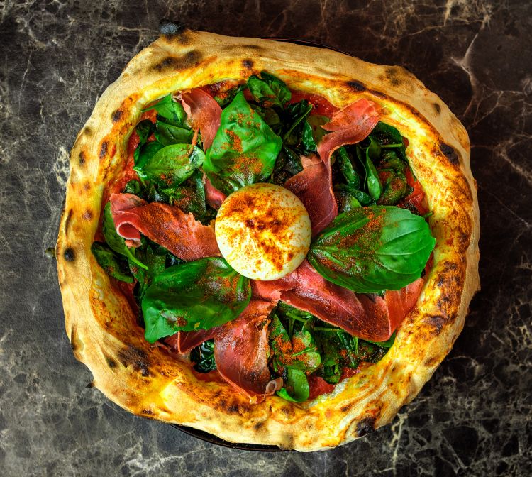 Una delle pizze speciali di Jurgen: la Spinacina con pomodoro pelato schiacciato a mano, fuori cottura spinacino condito con olio al limone e sale, burrata, prosciutto crudo di Parma 24 mesi, paprika dolce affumicata e basilico fresco