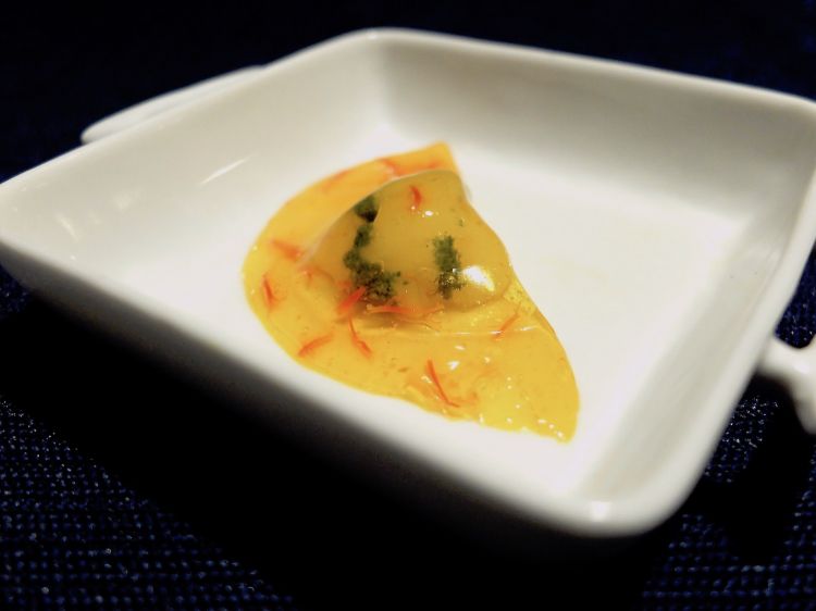 Raviolo d'acqua allo zafferano ripieno di gambero crudo e pesto. Il raviolo è fatto con un'infusione di zafferano gelificata
