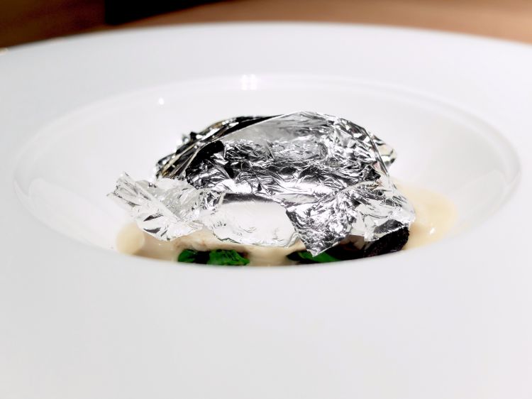 Branzino al cartoccio, olive candite e limone al sale: un piatto degli anni '80 rielaborato nel 2018, con foglie d'argento e fumetto di pesce
