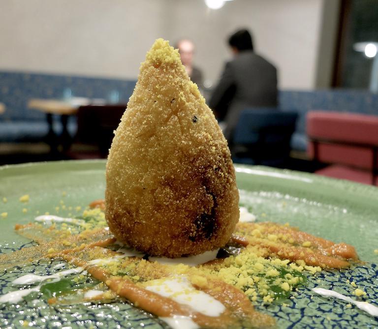 Il risotto in Sicilia: l'arancino, ossia arancino di riso allo zafferano ripieno di sugo di tre carni (vitello, manzo e maiale), uovo di quaglia e primosale, poi sugo di carne, fonduta di formaggio, salsa di basilico e uovo sodo sbriciolato. Leggi sopra: può essere utile un'opera di pulizia, ma il gusto arriva