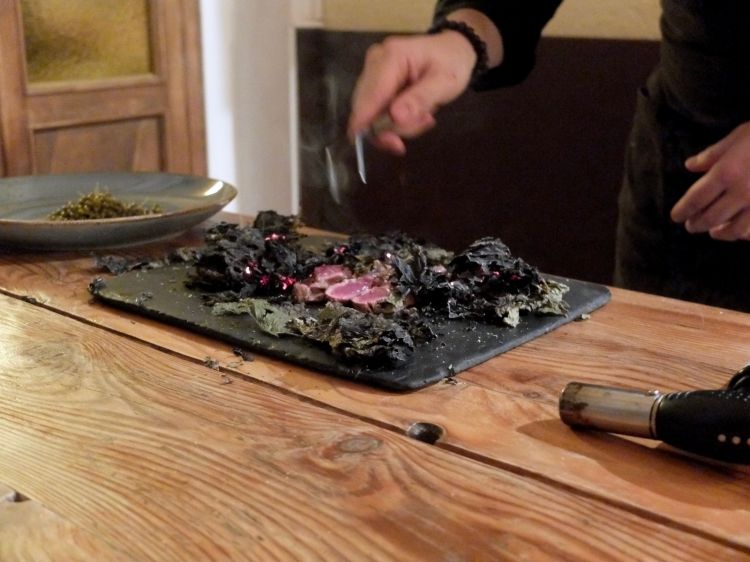 Al tavolo viene scottato un filetto di pecora gigante bergamasca racchiuso in foglie di frassino fermentate
