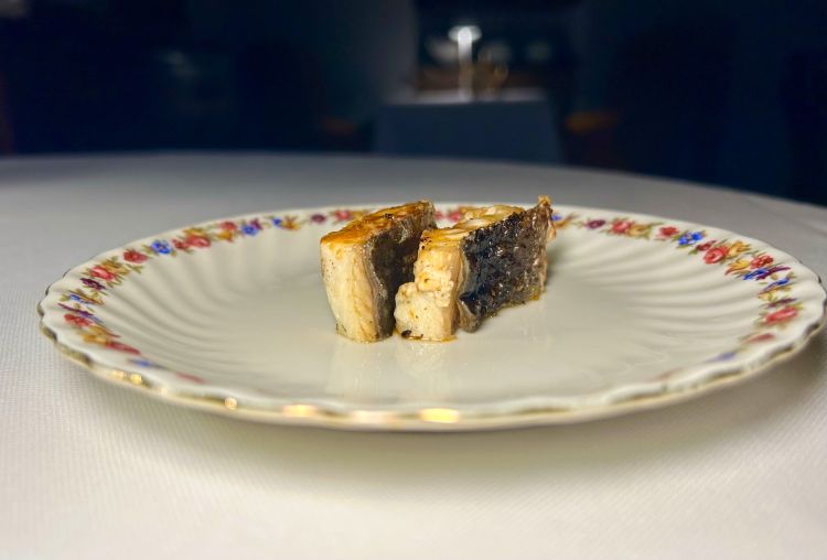 Dopo gli appetizer, che raccontiamo nel testo principale, ecco Anguilla - Purezza: l’anguilla è trattata attraverso un processo molto preciso. Viene inserito un ago nel midollo spinale e si utilizza acqua in pressione per dissanguarla completamente: l’obiettivo è eliminare impurità e componenti indesiderate, ottenendo una carne dal gusto più pulito. Segue una maturazione di dieci giorni in frigorifero con ozono, utilizzato per sterilizzare la carne, limitarne le alterazioni enzimatiche e renderne la consistenza più compatta. L’anguilla viene poi grigliata, in modo da sgrassarla, e ottenere esternamente una pelle croccante, internamente un morso turgido, come quello di un pesce oceanico. È condita con un fermentato che ricorda la salsa di soia, ottenuto utilizzando le proteine della testa e della coda dell’animale. Accanto arriva un brodo delicato ricavato dalle lische e un piccolo pezzo di interiora cotto al vapore. A completare il piatto, una pasta di semi verdi di nasturzio viene grattugiata e accompagnata da una fogliolina di nasturzio, per ottenere un effetto aromatico che richiama il wasabi
