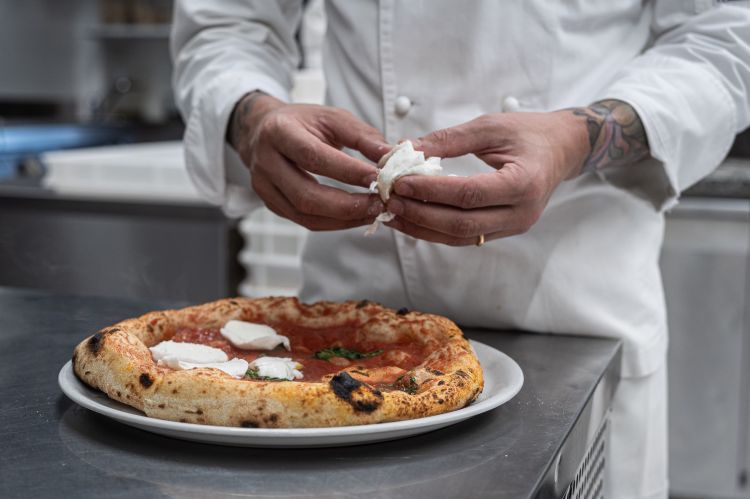 Le mani di Endrit al lavoro: la sua è una pizza napoletana dal cornicione croccante, frutto di un impasto da lui studiato per oltre un anno