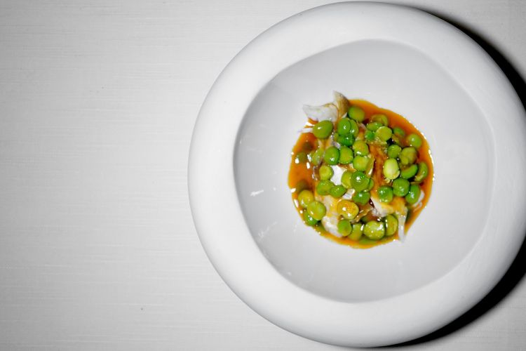 Testa di dentice arrosto con piselli in umido in guazzetto di pomodoro, come se fosse un cacciucco. La testa viene laccata con riduzione di bucce di verdura e cotta nelle foglie di fico. Strepitosa