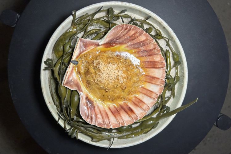 Capesanta arrostita, burro ai semi di zucca, nocciola, cotogna giapponese. «Arrostiamo le capesante, le rimettiamo nella loro conchiglia e prepariamo un burro di semi di zucca lattofermentati; poi cuociamo il tutto al forno con questo burro sopra, nocciole affettate e succo di cotogna giapponese». L'assaggio parte facile (capesanta + burro) e acquisisce complessità poco a poco, con la masticazione. Rimane semplice ma con effetto wow