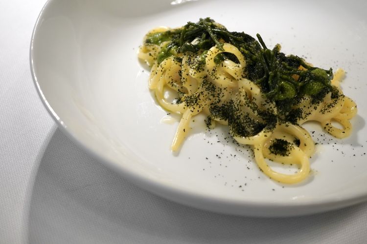 Spaghetti al doppio aglio e olio, salicornia, polvere di alga nori. Interessante, ma vediamo delle problematiche. Lo chef condisce lo spaghetto con una salsa costruita con spaghetti aglio e olio stracotti e poi frullati, che va a condire quindi altri spaghetti con crema di salicornia e olio al peperoncino. La scelta della pasta frullata diluisce troppo la componente aromatica e impone un eccesso di amidi
