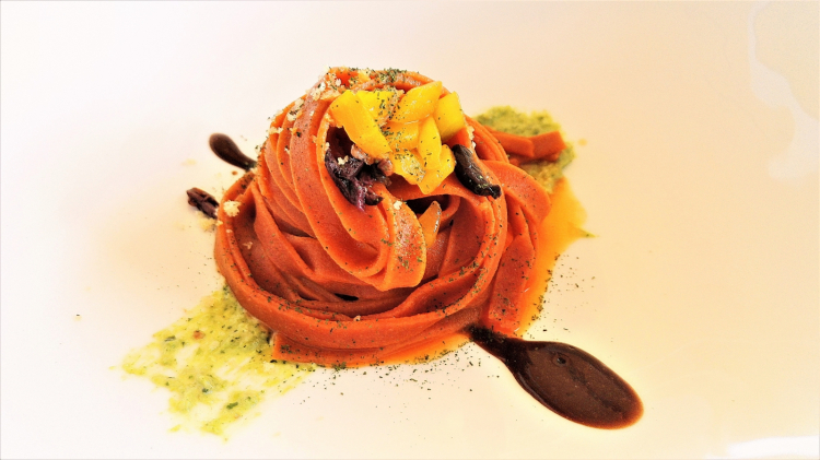 Nastrine di peperoni con alici, olive nere, pesto di peperoncini verdi di fiume, pistacchi su crema di aglio nero